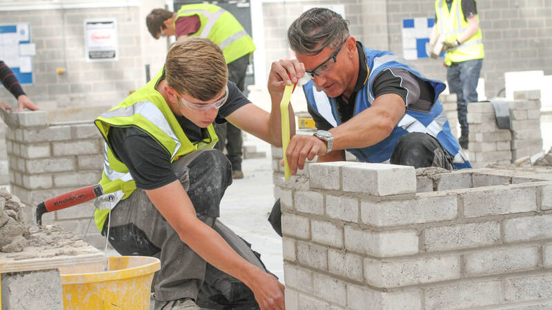 Person building a brick wall