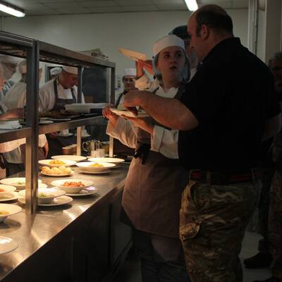 Lance Corporal Barry Sharp talking to students in the kitchens at the Orme View restaurant at Coleg Llandrillo
