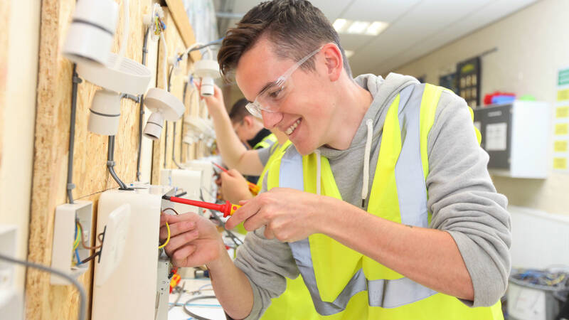 Coleg Menai learner fixing electrical outlet in classroom