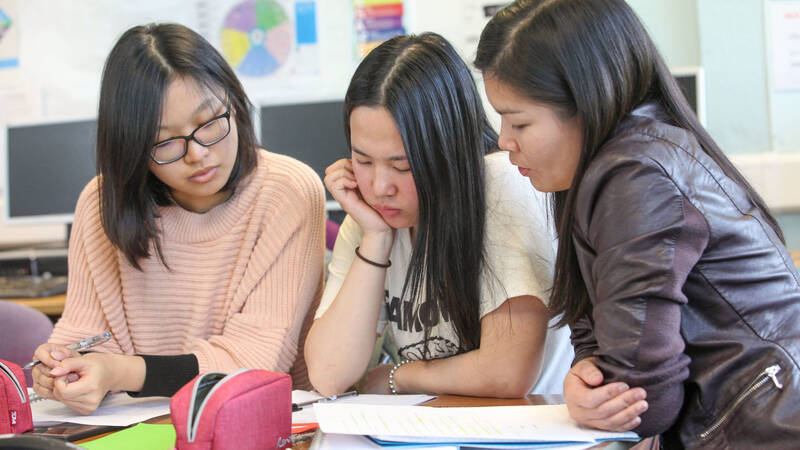 Three Coleg Menai learners working together in a classroom