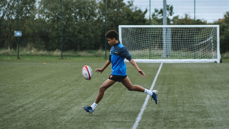 Student kicking a rugby ball