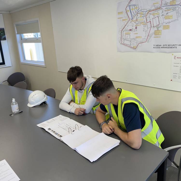 Ben Hughes (chwith) a Brody White yn adolygu cynlluniau tra oedden nhw ar brofiad gwaith gyda Read Construction
