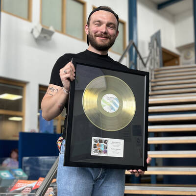Past student Krystian Koziński with the gold disc presented to him at Coleg Llandrillo