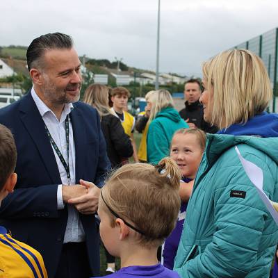 Lawrence Wood, Pennaeth Coleg Llandrillo gydag athrawon a disgyblion cynradd yng nghystadleuaeth pêl-droed yr Urdd ar y cae 3G