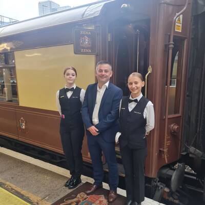 Rhian James and Yuliia Batrak with lecturer Glenydd Hughes in front of the British Pullman train