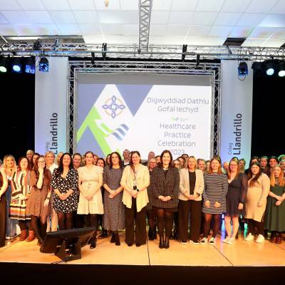 Healthcare support workers on stage at Venue Cymru after completing their Healthcare Practice Level 4 Certificate in Higher Education