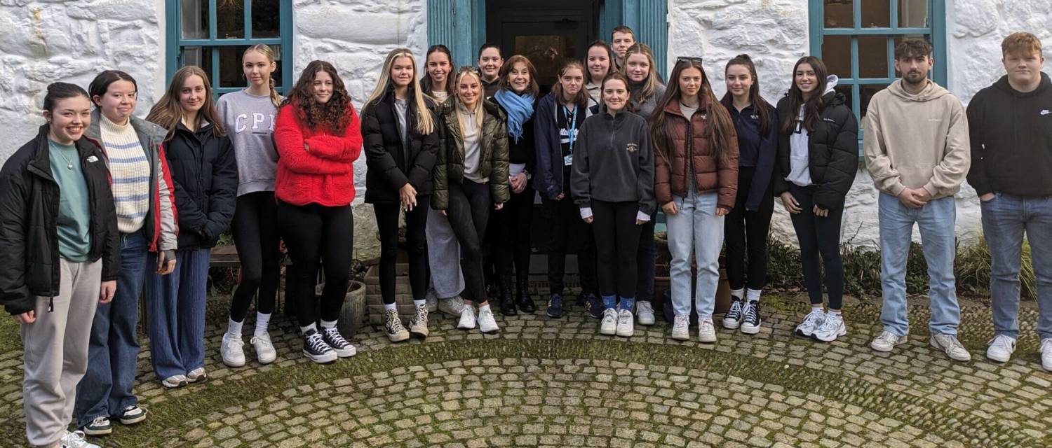 Myfyrwyr Safon Uwch o Goleg Meirion-Dwyfor y tu allan i Ganolfan Ysgrifennu Tŷ Newydd gyda'r Prifardd Mererid Hopwood.