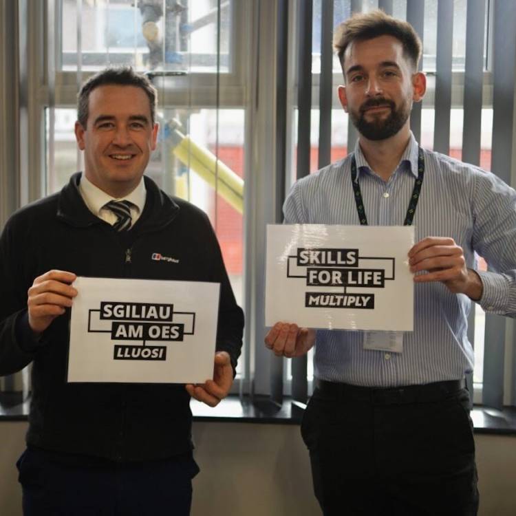 Vale of Clwyd MP Dr James Davies and Alex Carter of Multiply holding up posters saying Sgiliau Am Oes: Lluosi / Skills For Life: Multiply