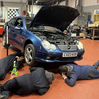 People working on a car as part of the Basic Car Maintenance course offered by Multiply at Coleg Menai in Llangefni