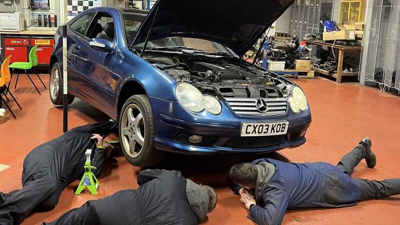 People working on a car as part of the Basic Car Maintenance course offered by Multiply at Coleg Menai in Llangefni