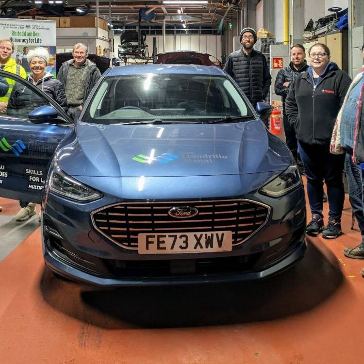 People working on a car as part of the Basic Car Maintenance course offered by Multiply at Coleg Menai in Llangefni