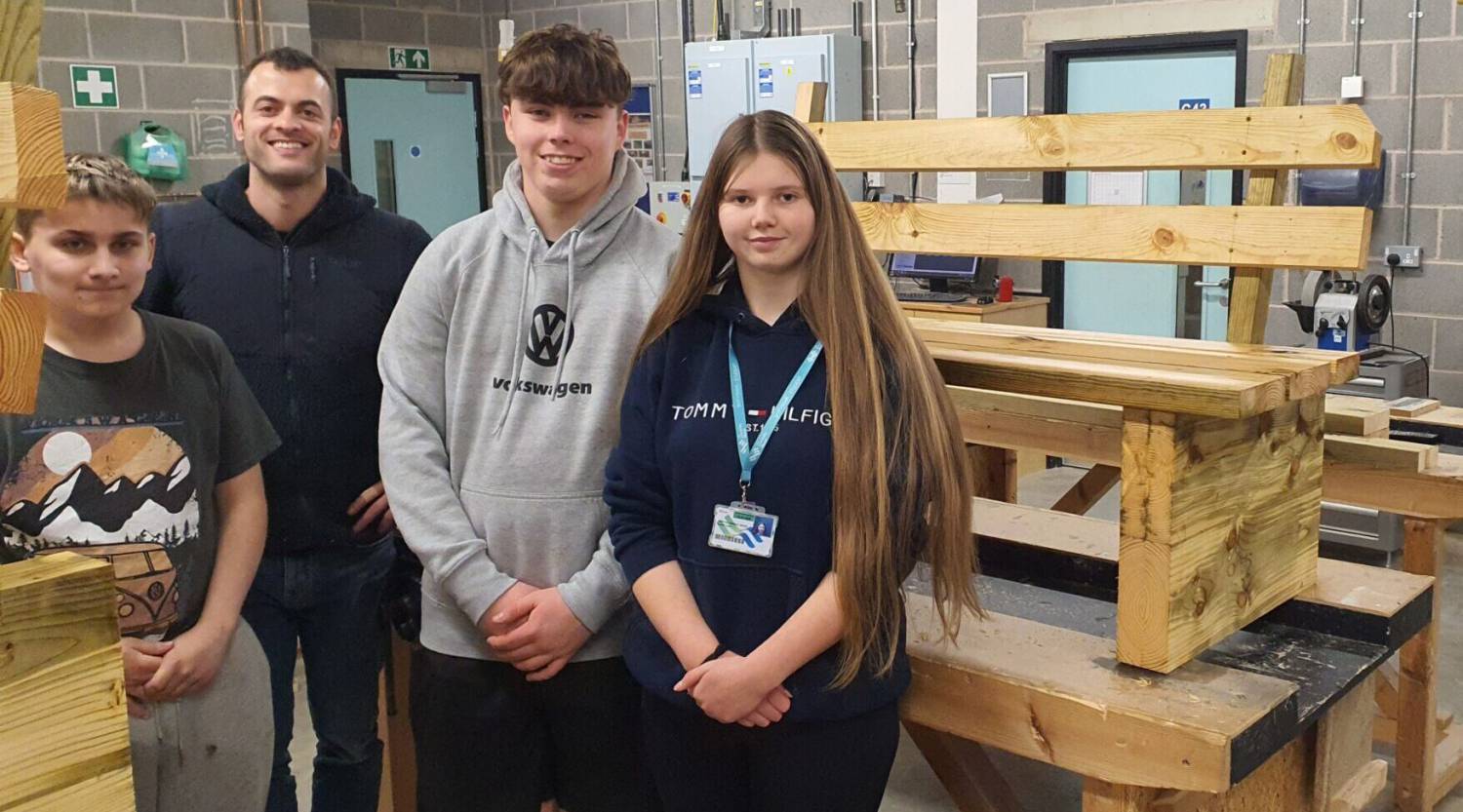 Thomos Evans, Luke Owen Hughes and Scarlet Lewis with practical skills supervisor Tom Coulthard in the carpentry workshop at Coleg Menai