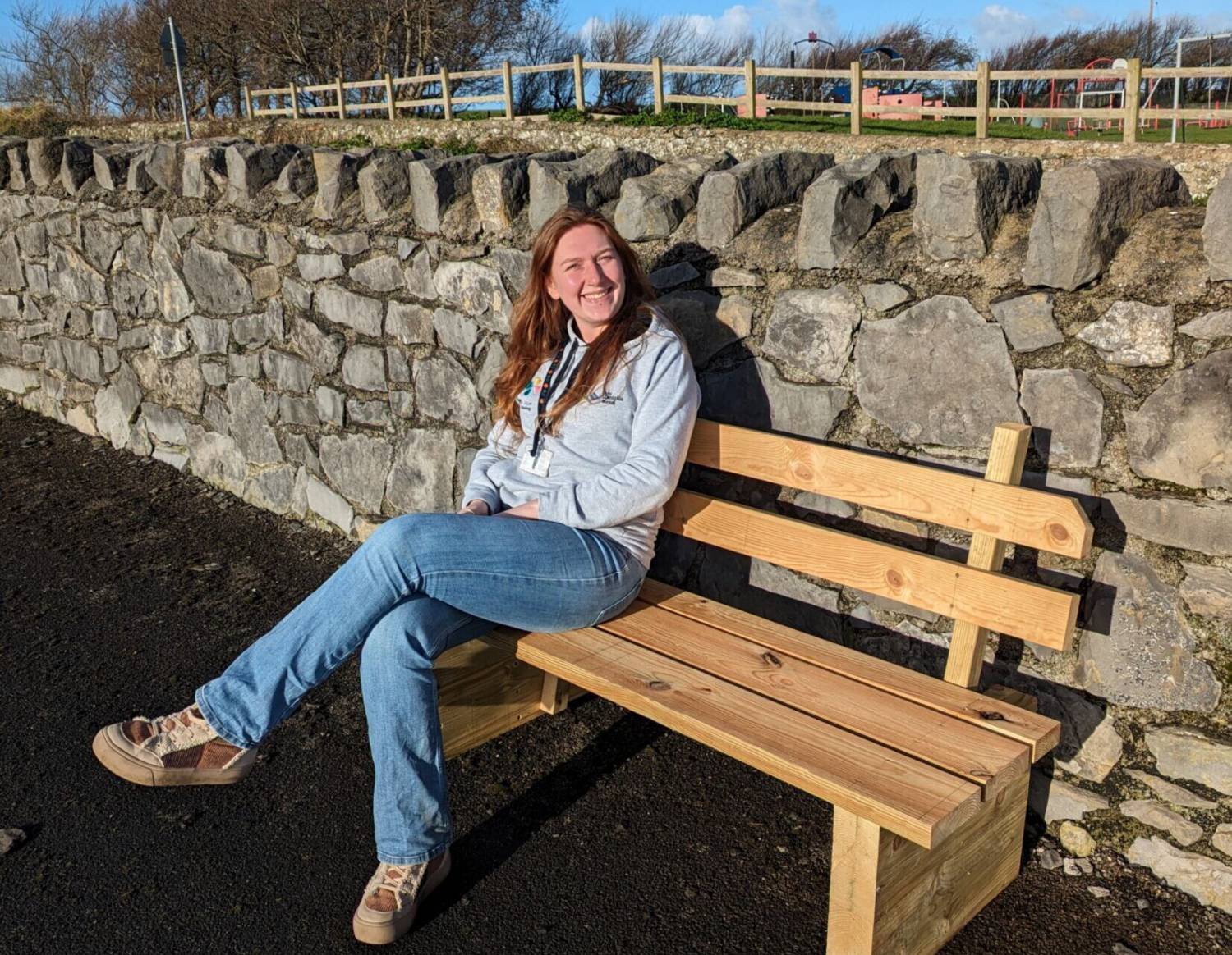 Wellbeing Activity Officer Naomi Grew with the bench made by Wellbeing Ambassadors at the cemetery in Aberffraw