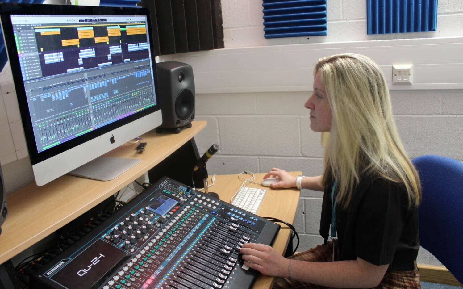 Hannah Popey using a mixing desk in a recording studio at Coleg Llandrillo