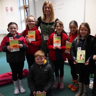 Casia Wiliam with schoolchildren holding copies of her book Sara Mai ac Antur y Fferm at Glynllifon