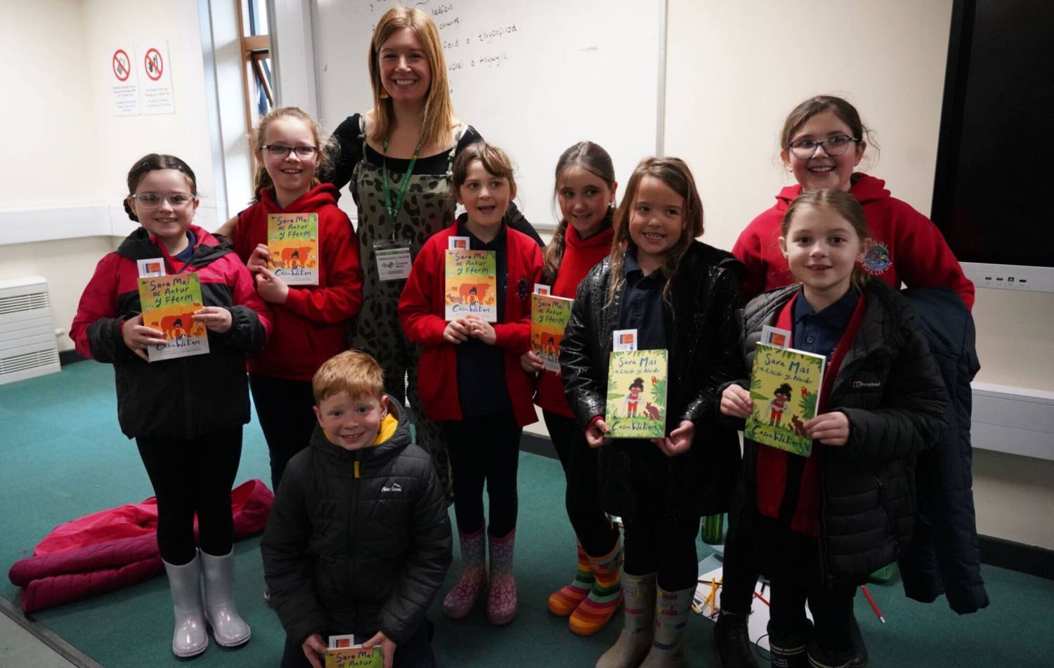 Casia Wiliam with schoolchildren holding copies of her book Sara Mai ac Antur y Fferm at Glynllifon
