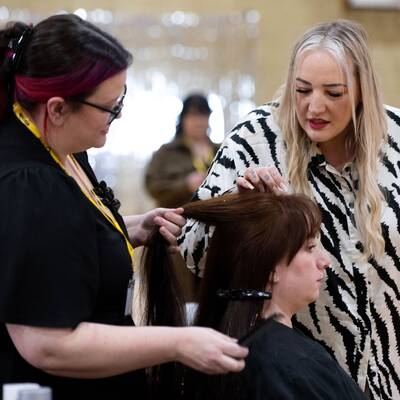 Coleg Llandrillo student Ceri Thomas talking to judge Lisa Farrell while competing at the 2024 Concept Hair Learner of the Year final
