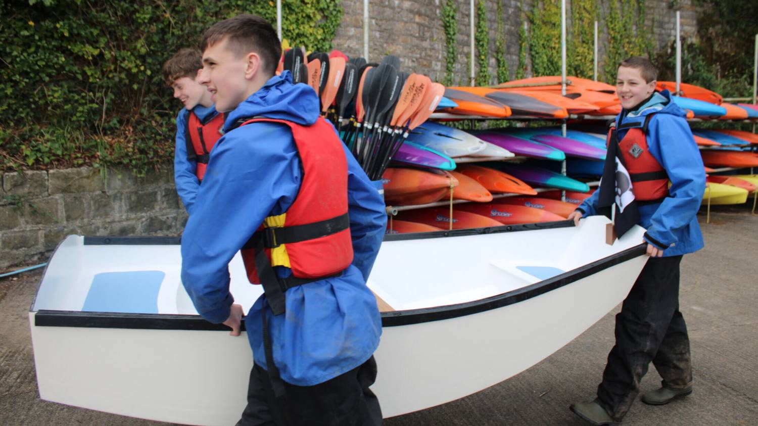 Myfyrwyr yn cario dingi yng Nghanolfan Conwy yn Llanfairpwll