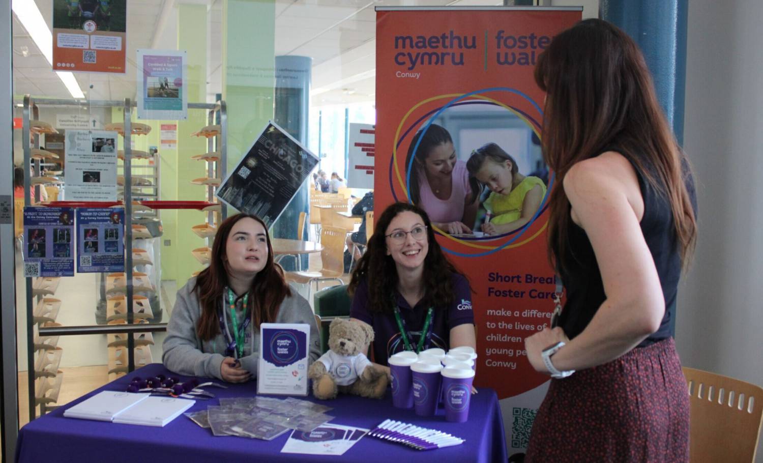 Staff Maethu Cymru yn cynnal stondin yn y dderbynfa ar gampws Coleg Llandrillo yn Llandrillo-yn-Rhos
