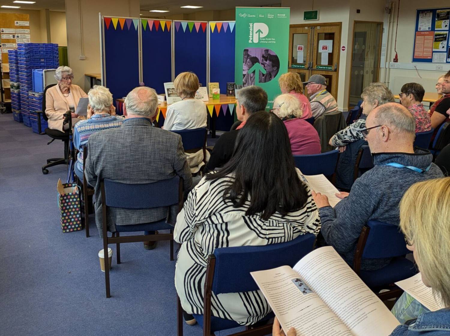 A learner reading out her work at the launch of a creative writing booklet in the library at Coleg Menai’s Bangor campus