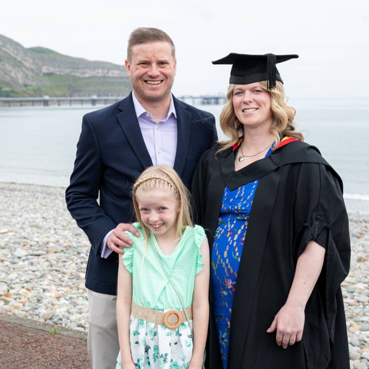 Hannah Hughes a'i theulu ar y Promenâd yn Llandudno yn barod i raddio