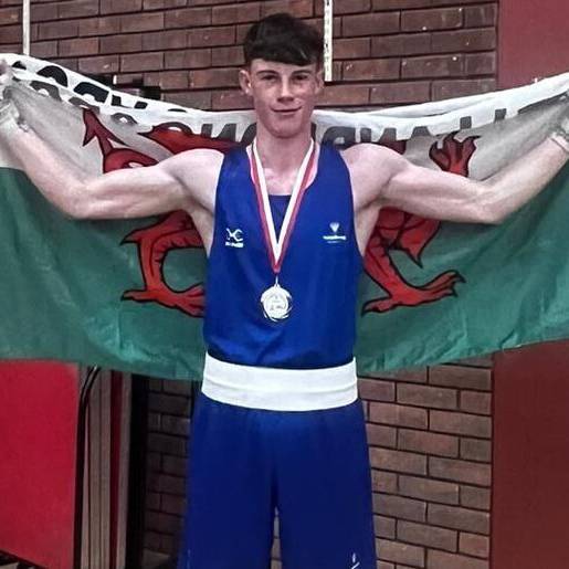 Mitchel Jones wearing his GB Championship gold medal and holding a Wales flag