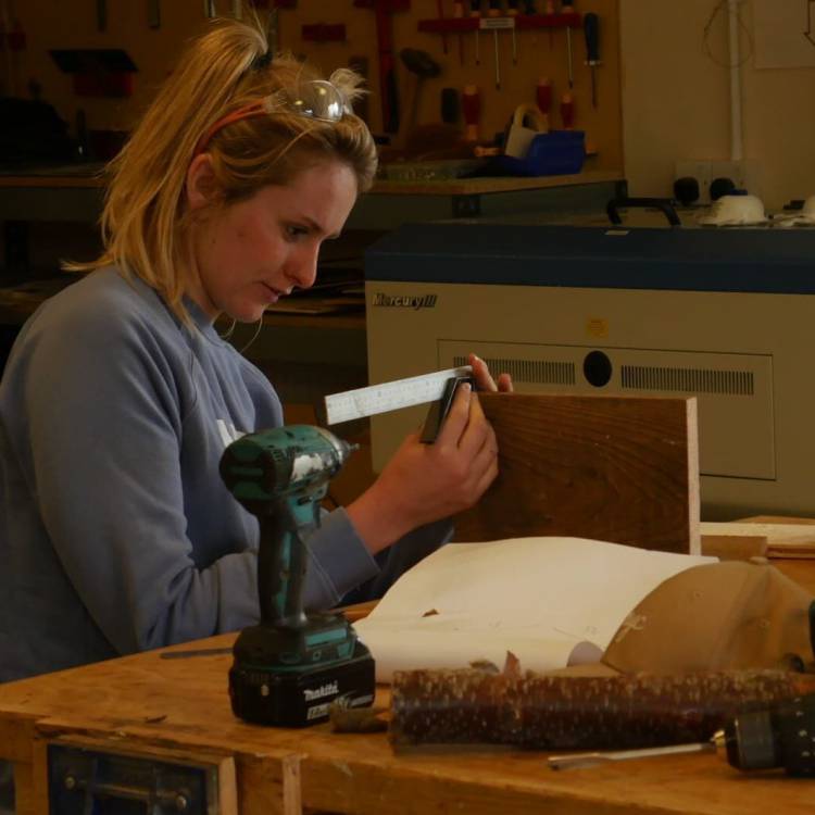 Dysgwr ar y rhaglen Lluosi, yn mesur pren yn ystod cwrs Sgiliau Gwaith Coed a Rhifedd Ymarferol