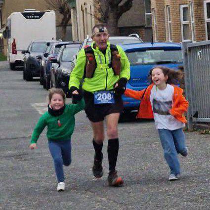 Tecwyn Jones yn rhedeg at linell derfyn Marathon Ultra'r Gaeaf Pen Llŷn gyda'i wyresau Tesni a Casi