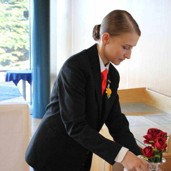 Yuliia Batrak, myfyrwraig lletygarwch o Goleg Llandrillo, yn gosod bwrdd ar gyfer y gystadleuaeth