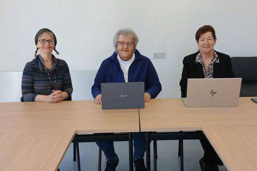 Pobl yn Neuadd Bentref Llanddona gyda gliniaduron a ddarparwyd gan Lluosi