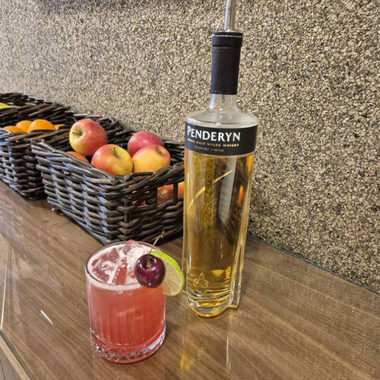 A cherry whisky sour made by Coleg Llandrillo student Yuliia Batrak next to a bottle of Penderyn Madeira Finish