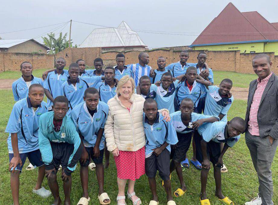 Boys in Burundi wearing Coleg Menai football kits, pictured with Reverend Pauline Edwards of Annie’s Orphans