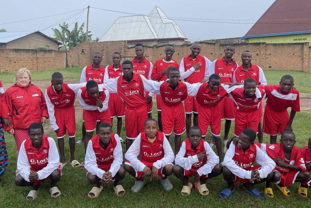Boys in Burundi wearing Welsh Colleges Sport football kits, pictured with Reverend Pauline Edwards of Annie’s Orphans