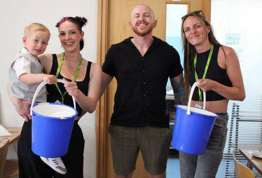 Students Loren Williams (left) and Emma Orr holding collection buckets with Conwy Mind fundraiser Kieran Davenport at Coleg Llandrillo