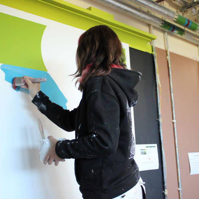 Cystadleuydd yn peintio wal yn rownd ranbarthol Cystadleuaeth Prentis Paentio ac Addurno'r Flwyddyn yng Ngholeg Llandrillo