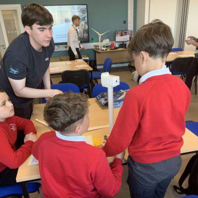 An RWE apprentice helping children from Ysgol Emmanuel building model wind turbines from a kit