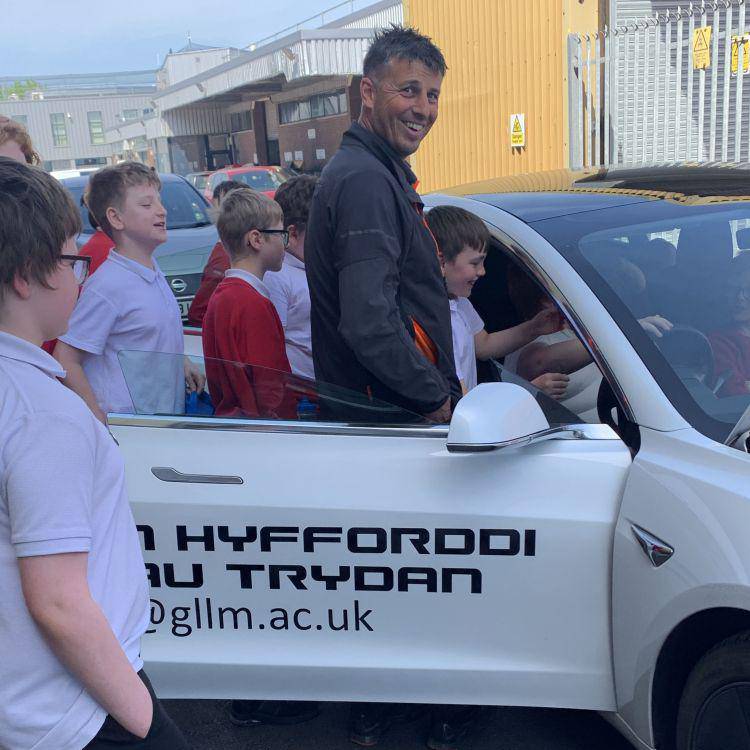 Coleg Llandrillo engineering lecturer Arron Peel showing Ysgol Emmanuel pupils a Tesla at the Rhyl campus