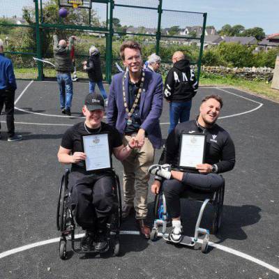 Cyn-fyfyrwyr o Goleg Menai, Ryan a Kieran Jones ar y cwrt pêl-fasged newydd ym Mharc Mwd gyda'r Cynghorydd Neil Tuck