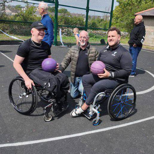 Former Coleg Menai students Ryan and Kieran Jones on the new basketball court at Parc Mwd with Councillor Ken Taylor