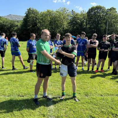 Rugby engagement officer Ollie Coles presenting the North Wales Cup to Huw Watkins, captain of Glynllifon’s rugby team