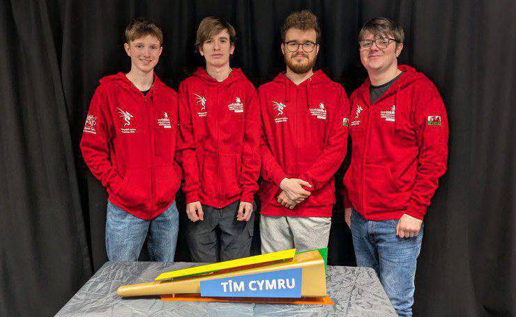 Aron Hughes, Matthew Owen, Cai Owen a Guy Geurtjens, myfyrwyr yn adran cyfryngau creadigol Coleg Menai, gyda fflam Tîm Cymru