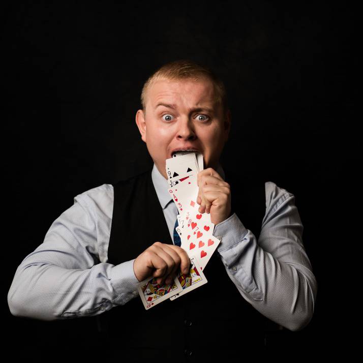 A promotional picture of Dean Raymond performing a magic trick with playing cards