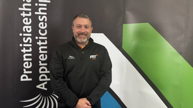 Mally Tidswell yndi Prif Prentis y Flwyddyn. Mae o'n gweithio i Gyngor Sir Conwy (Ffit Conwy)