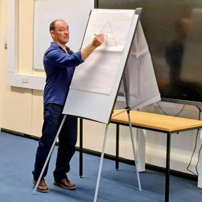 Author, Cynan Jones standing at the front of a classroom writing on a large sheet of paper.