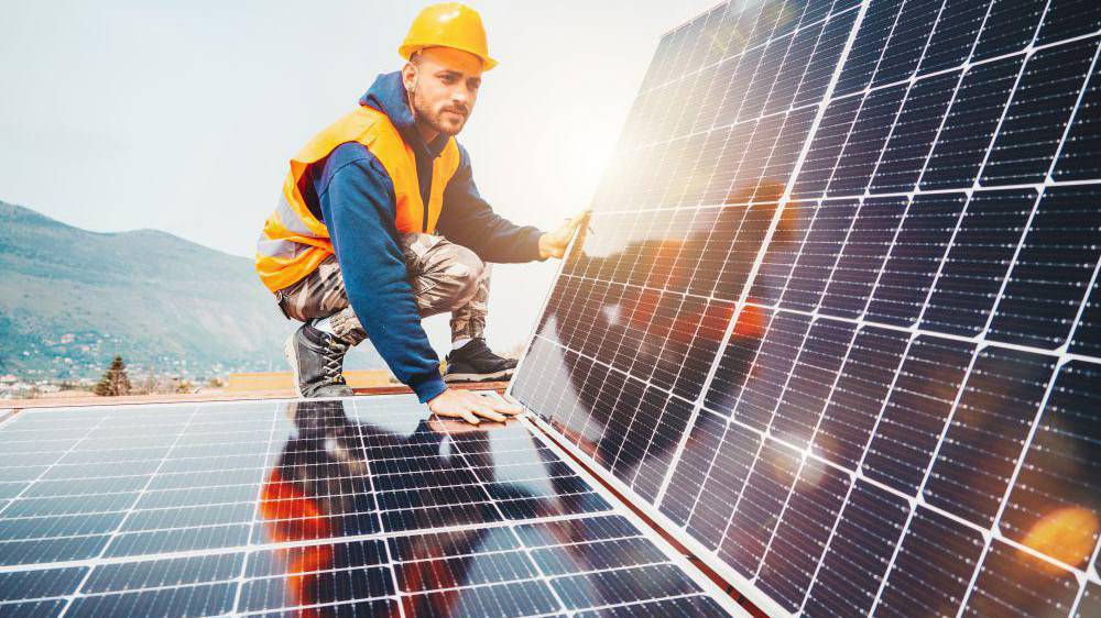 Worker assembles energy system with solar panel for electricity