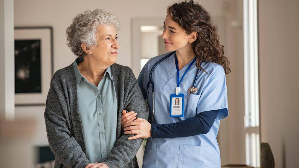 Caregiver assists an elderly woman at care home