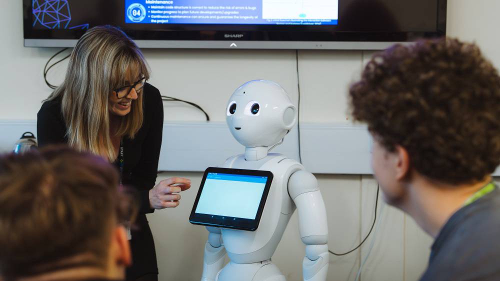 Darlithydd yn dysgu myfyrwyr am AI a roboteg