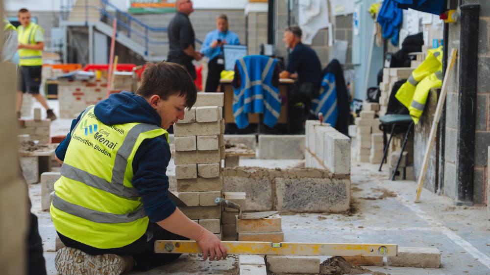 Dysgwyr yn sicrhau fod y wal frics yn lefel