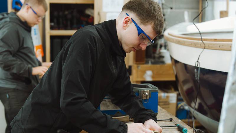 Myfyriwr peirianneg forol yn gweithio ar gwch