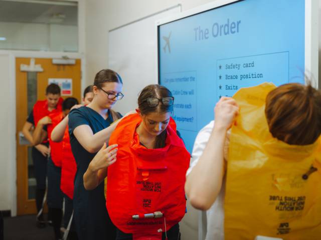 Travel and tourism learners being taught how to wear a life jacket